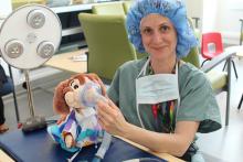 Exam station 3 is a teddy bear-sized version of an Operating Room Table coordinated by Child Life Specialist, Sabrina, who shows patients how to make sure a mask is properly fitted on each teddy bear before an operation. 